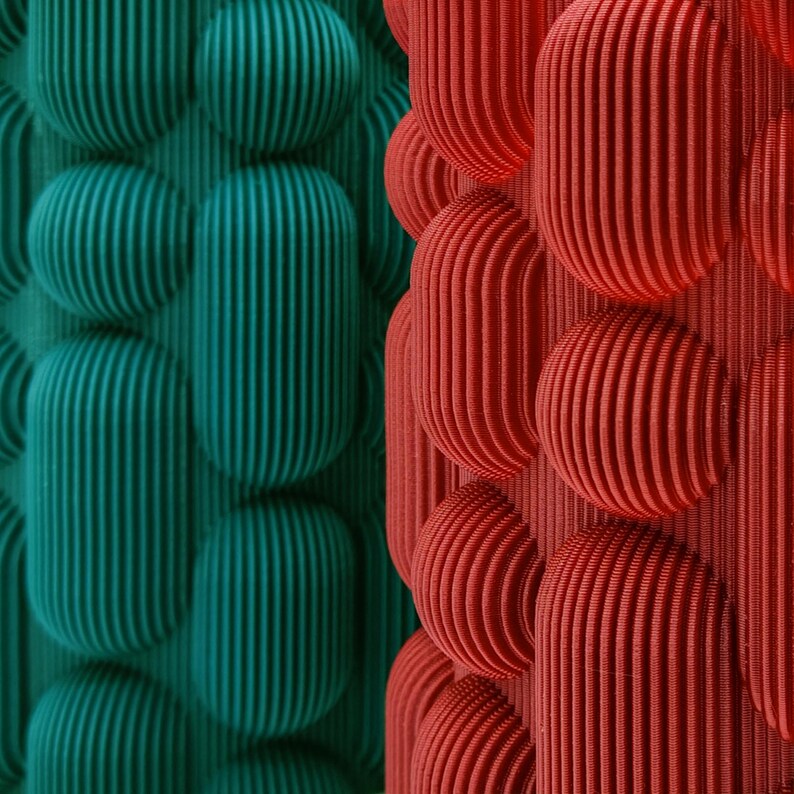 May include: Abstract image featuring a repeating pattern of textured, rounded shapes. The design is split vertically, with teal-green forms on the left and red forms on the right. The shapes have a ribbed texture, creating a 3D effect.