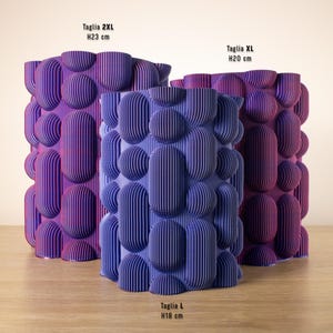 May include: Three decorative vases in shades of purple and blue, with a textured, bubble-like design. The largest vase is 23 cm tall, the medium vase is 20 cm tall, and the smallest vase is 18 cm tall. The vases have vertical lines.