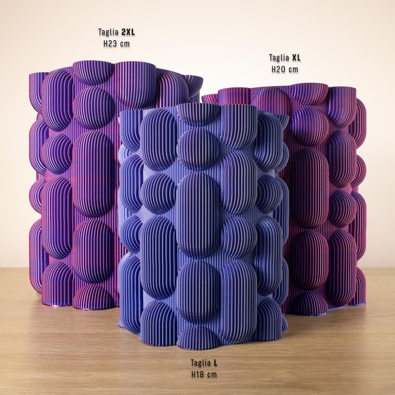 May include: Three decorative vases in shades of purple and blue, with a textured, bubble-like design. The largest vase is 23 cm tall, the medium vase is 20 cm tall, and the smallest vase is 18 cm tall. The vases have vertical lines.