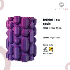 May include: A purple and magenta decorative object with a textured, rounded design. The object has vertical lines and a unique shape. Text on the right says "Definisci il tuo spazio: scegli taglia e colore." and "Crafted, not just made."