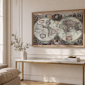 Op de afbeelding: Een grote rechthoekige wandkunstprint met een vintage wereldkaart in twee hemisferen, voorzien van gedetailleerde illustraties, decoratieve randen en Latijnse tekst, ingelijst in een lichtgekleurde houten lijst.