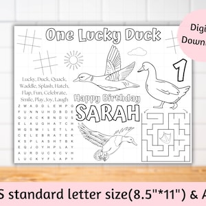 May include: A black and white printable activity sheet for a child's first birthday. The sheet features a duck theme with the words "One Lucky Duck" and "Happy Birthday SARAH". The sheet includes a word search, a maze, and a connect-the-dots activity. The sheet is designed to be printed on standard letter size paper (8.5" x 11").