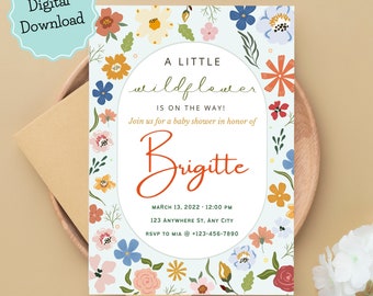 Puede incluir: Una invitación de baby shower azul claro con un borde floral. El texto dice "A Little Wildflower is on the way!" y "Join us for a baby shower in honor of Brigitte". También se incluye la fecha, la hora, la dirección y la información de RSVP.