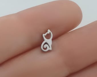 May include: A silver charm in the shape of a cat. The charm is small and delicate, and it would be perfect for a necklace or bracelet.