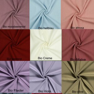May include: A collection of 15 fabric swatches in various colors, including moss green, copper, mint, red, blue, cream, mauve, lavender, olive, and gray. Each swatch is labeled with a German word describing the color, such as "Bio moosgr&uuml;n" for moss green.
