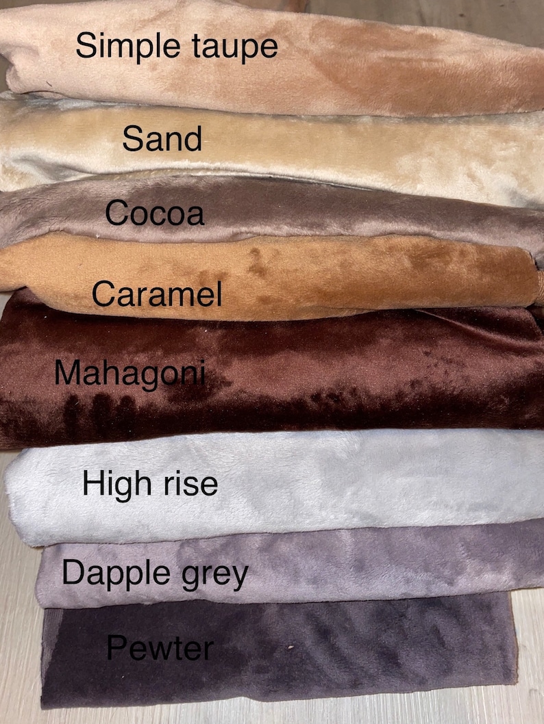 May include: A stack of eight fabric swatches in different shades of brown, gray, and beige. The swatches are labeled with the following names: Simple Taupe, Sand, Cocoa, Caramel, Mahogany, High Rise, Dapple Grey, and Pewter.