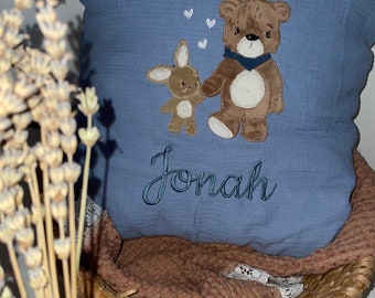 May include: A blue pillow with a brown bear and bunny embroidered on it. The pillow has the name "Jonah" embroidered on it.