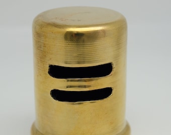 May include: A gold metal drain stopper with two holes. The stopper is designed to fit over a drain pipe.