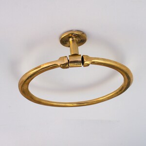 Puede incluir: Un anillo para toalla de metal dorado montado en un techo blanco.