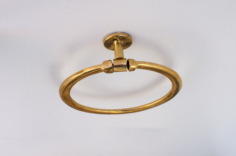Puede incluir: Un anillo para toalla de metal dorado montado en un techo blanco.