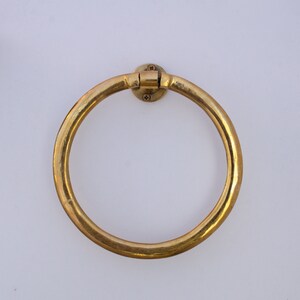 Puede incluir: Un anillo para toallas de metal dorado montado en una pared blanca.