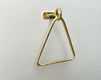 May include: A gold triangle towel rack with a rounded top. The rack is mounted to a white wall.
