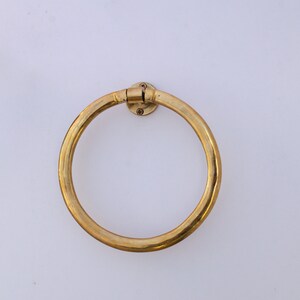 Puede incluir: Un anillo para toallas de metal dorado montado en una pared blanca.