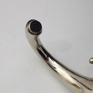 Pode incluir: Uma torneira cromada com uma &uacute;nica alavanca e um bico curvo. O bico tem um arejador redondo preto.