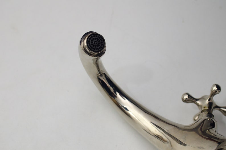 Pode incluir: Uma torneira cromada com uma &uacute;nica alavanca e um bico curvo. O bico tem um arejador redondo preto.