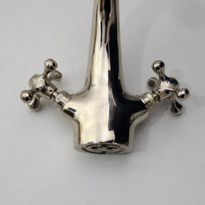 Pode incluir: Uma torneira cromada polida com duas al&ccedil;as em forma de cruz.