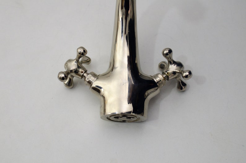 Pode incluir: Uma torneira cromada polida com duas al&ccedil;as em forma de cruz.