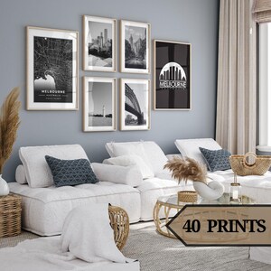 May include: A living room with a white sectional sofa and a coffee table. The walls are painted a light gray and there are five black and white framed prints on the wall. The prints feature cityscapes and a bridge. The text "MELBOURNE AUSTRALIA" is visible on two of the prints.
