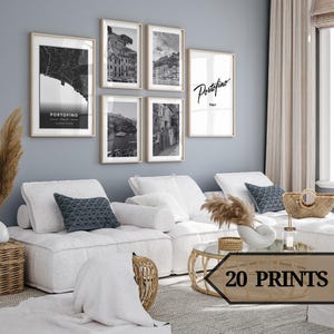 Peut inclure: Un ensemble de six impressions en noir et blanc représentant des images de la ville italienne de Portofino. Les impressions sont disposées en grille sur un mur au-dessus d'un canapé blanc avec des coussins. Le texte "Portofino, Italie" est visible sur l'une des impressions.