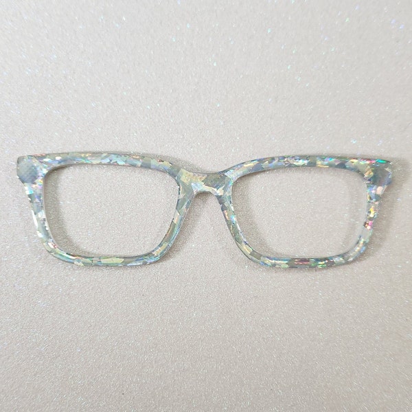 May include: A pair of iridescent glasses with a square frame. The glasses are made of a clear material with a glittery finish.