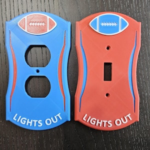 May include: Two light switch covers with a football design. One is blue with a red football and the other is red with a blue football. Both covers have the text "Lights Out" on the bottom.