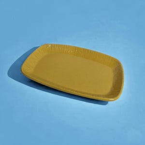 May include: A rectangular, yellow ceramic serving tray with a textured surface.