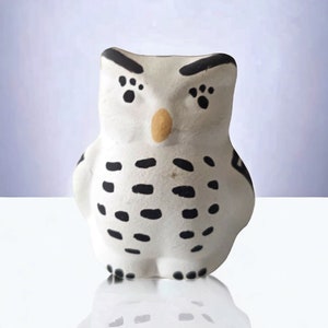 May include: White ceramic owl figurine with black and brown markings. The owl has a round body and large eyes.