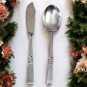 May include: A set of two vintage silver-plated serving utensils. The butter knife and spoon feature a floral design on the handle.