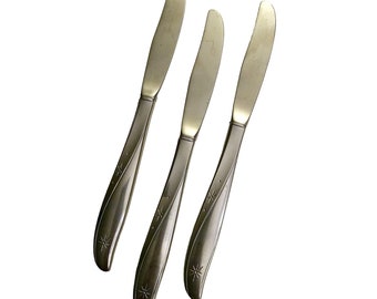 May include: Three silver butter knives with a star design on the handle.