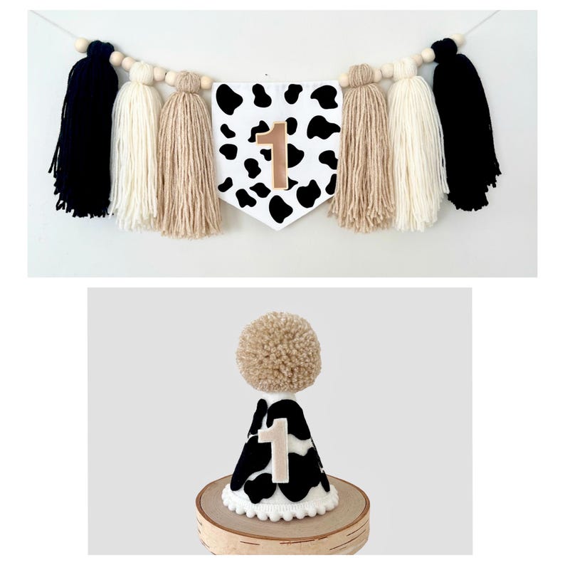 May include: A black and white cow print party banner with a gold number one. The banner is strung with white, black, and tan tassels. A matching cow print party hat with a gold number one is also shown.