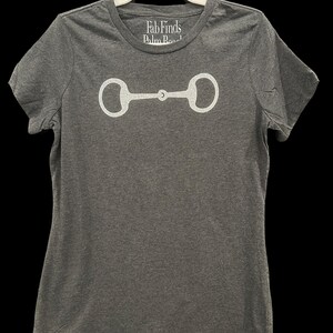 May include: Gray t-shirt with a white outline of a horse bit. The shirt has the text "Fab Finds Palm Beach" on the front.