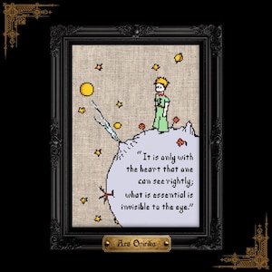 May include: A framed cross-stitch embroidery on beige fabric featuring a character with yellow hair, a green outfit, and red scarf standing on a small planet with stars. The text reads, "It is only with the heart that one can see rightly; what is essential is invisible to the eye."
