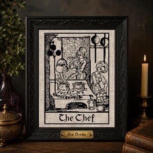 Peut inclure: Une broderie au point de croix en noir et blanc représentant une scène de cuisine avec un chef, encadrée dans un cadre rectangulaire noir orné. Le texte "The Chef" est brodé en bas et une petite plaque dorée indique "Ars Onirika".