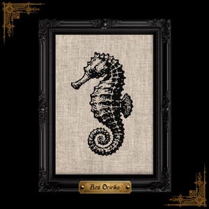 May include: A black cross-stitch seahorse design on a beige linen fabric background, encased in a black ornate frame. A small gold-toned plaque at the bottom of the frame features the text Ars Onirika in a dark, stylized font.