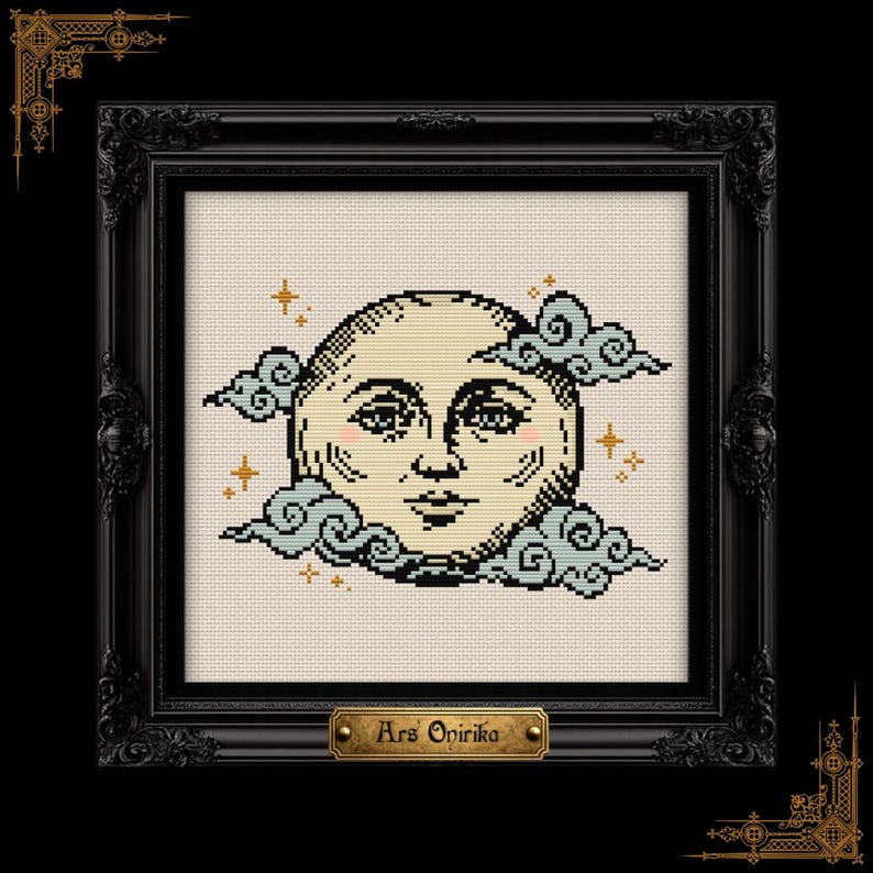 May include: A cross-stitch embroidery featuring a cream-colored moon with a human face, surrounded by light blue clouds and small gold stars. The piece is enclosed in a black ornate frame with a gold plaque at the bottom reading Ars Onirika.