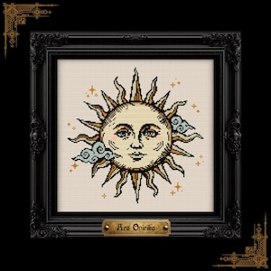 May include: A cross-stitch embroidery featuring a central sun face with golden rays, surrounded by small blue clouds and tiny star accents. The piece is enclosed in a black ornate frame with a gold-colored plaque at the bottom reading Ars Onirika.