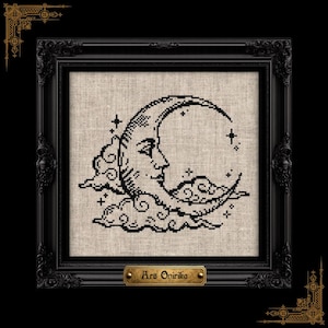 May include: A black cross-stitch embroidery on light beige linen fabric featuring a crescent moon with a human face surrounded by clouds and stars. The piece is housed in a black ornate frame with a small gold plaque reading Ars Onirika.