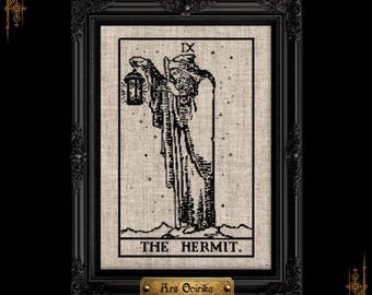 Puede incluir: Un bordado en punto de cruz enmarcado sobre tela beige con una ilustración de líneas negras de la carta del tarot El Ermitaño, que representa a una figura encapuchada con una linterna y un bastón, con el texto IX y THE HERMIT. Una placa dorada dice Ars Onirika.