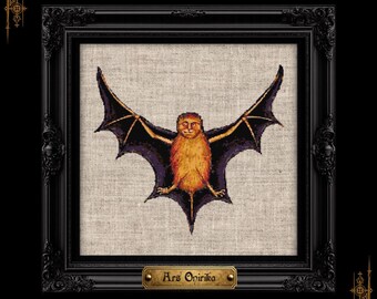May include: A cross-stitch embroidery of a bat with a human-like face, featuring orange fur and dark purple wings, centered on a light beige fabric. The piece is housed in a black ornate frame with a gold plaque reading Ars Onirika.