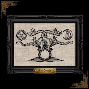 Puede incluir: Un bordado de punto de cruz negro sobre tela beige claro que muestra un dragón de dos cabezas sobre un círculo, flanqueado por un sol y una luna creciente. La pieza está en un marco negro ornamentado con una placa dorada Ars Onirika.