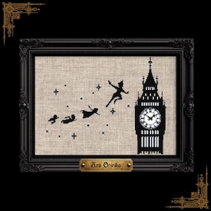May include: A cross-stitch embroidery on light beige fabric featuring a black silhouette of a clock tower and four figures flying through the air with small white stars. The piece is housed in a black ornate frame with a gold plaque reading Ars Onirika.