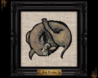 May include: A cross-stitch embroidery of a curled-up brown cat on light-colored fabric, housed in an ornate black frame. A small gold-toned plaque at the bottom of the frame features the text Ars Onirika in a dark, stylized font.