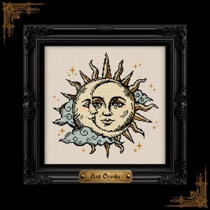 May include: A cross-stitch embroidery featuring a sun and moon with human faces, surrounded by clouds and small stars. The design is rendered in shades of gold, cream, and blue, enclosed in a black ornate frame with a plaque reading Ars Onirika.