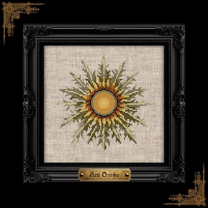 May include: A cross-stitch embroidery of a stylized sun with yellow, orange, and olive green rays on a light beige linen fabric. The piece is housed in a black ornate frame with a small gold plaque at the bottom featuring the text Ars Onirika.