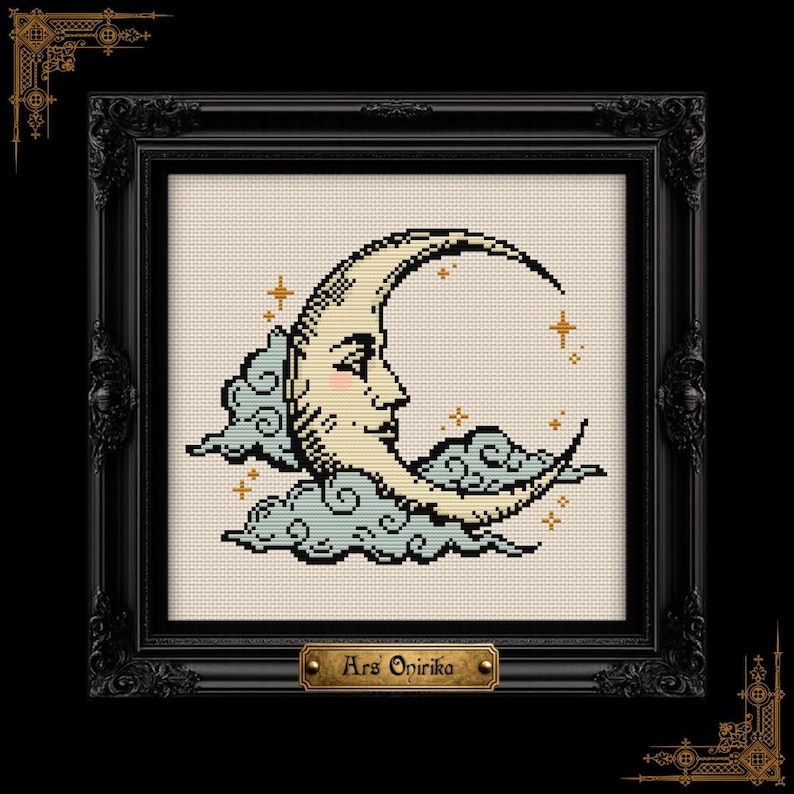 May include: A cross-stitch embroidery featuring a crescent moon with a human face, pink cheeks, and gold stars, surrounded by light blue clouds on a cream fabric background, encased in a black ornate frame with a plaque reading Ars Onirika.