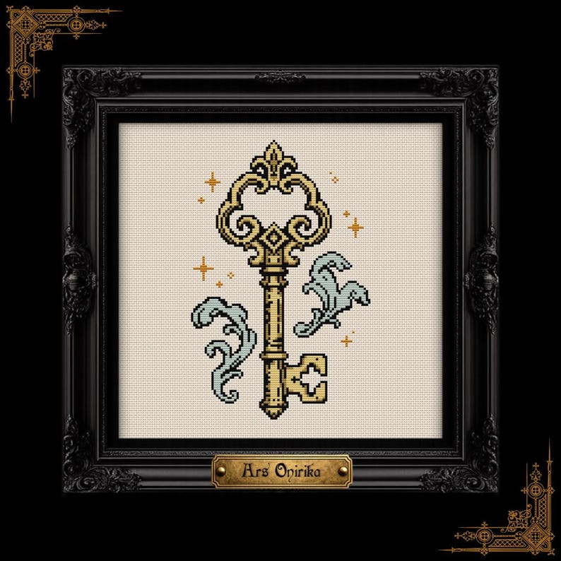 May include: A cross-stitch embroidery featuring a gold-colored ornate key with light blue decorative flourishes and small gold star accents on a cream-colored fabric background, encased in a black frame with a plaque reading Ars Onirika.