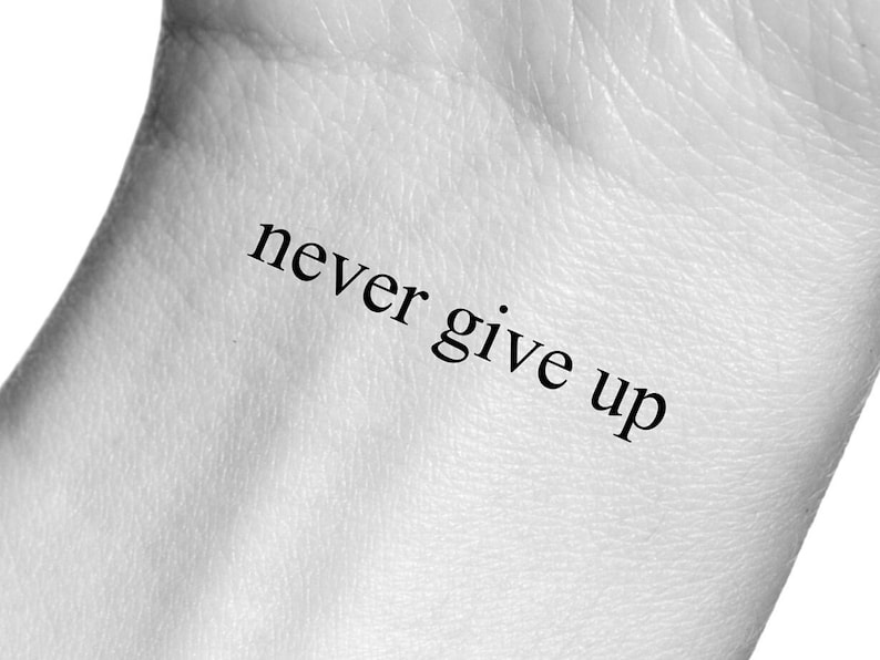 Może przedstawiać: Zbliżenie na nadgarstek osoby z tymczasowym tatuażem z napisem "never give up".