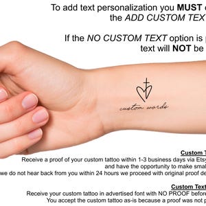 May include: A close-up of a hand with a small tattoo of a heart and cross with the text "custom words" below. The image includes text explaining that you must choose the "ADD CUSTOM TEXT" option to add text personalization to the tattoo. If you choose the "NO CUSTOM TEXT" option, no text will be added.