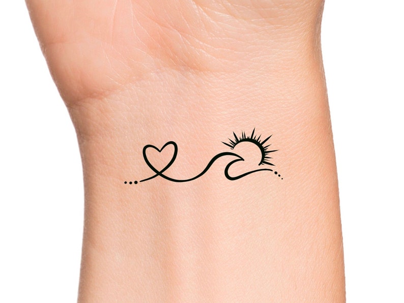 May include: A simple black line drawing tattoo design of a heart, wave, and sun on a person's wrist.