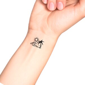 May include: A black and white temporary tattoo of a palm tree, sun, and wave.